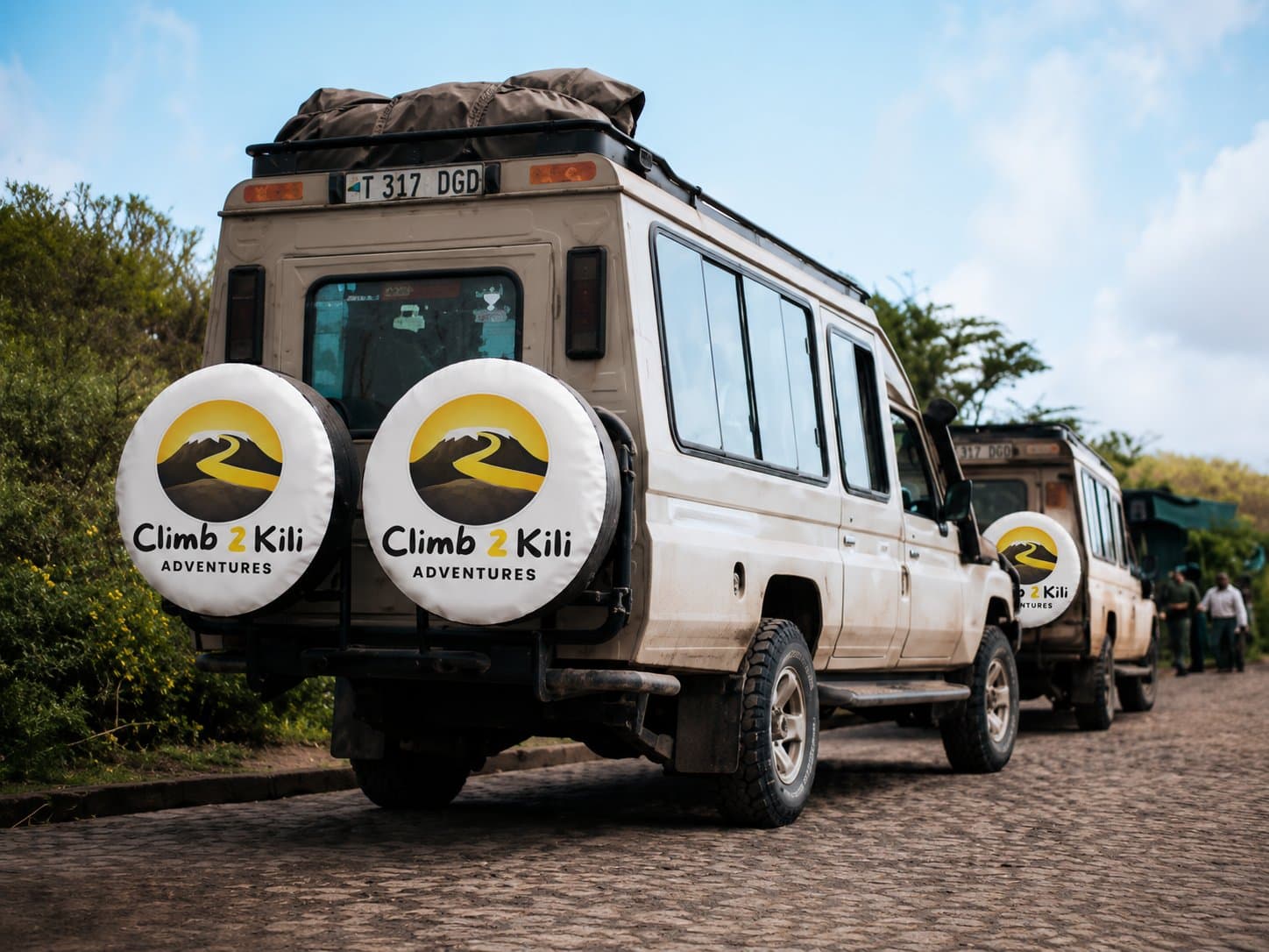 Stichter staan met Kilimanjaro gidsen, portiers, chefs, chauffeurs, en lokale gemeenschap leden onder de berg Kilimanjaro